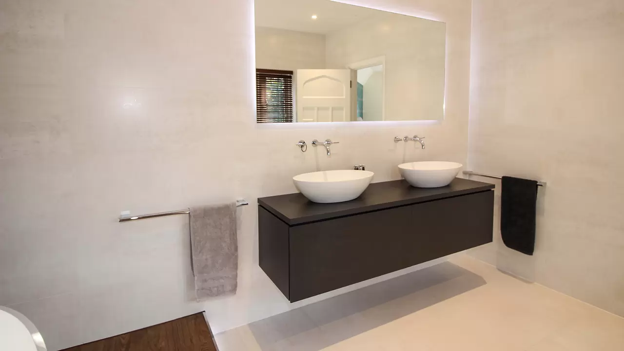 A wall-mounted vanity unit with two washbasins and mirror above
