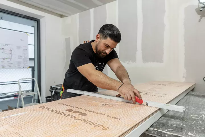 Schl&uuml;ter-Systems contractor cutting Schl&uuml;ter-KERDI-BOARD with a cutter knife.