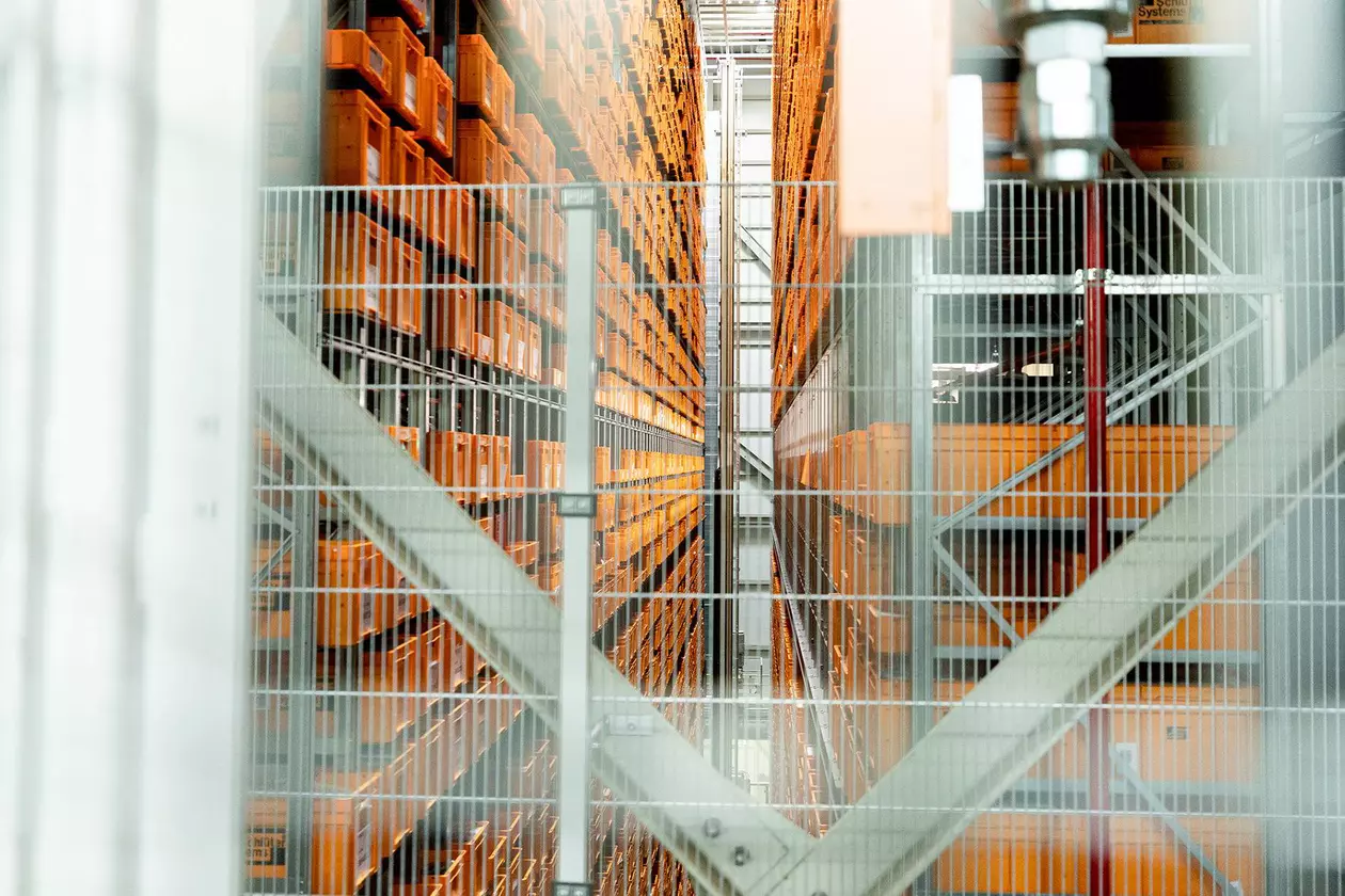 Hohe Regalreihen, gef&uuml;llt mit orangefarbenen Transportboxen