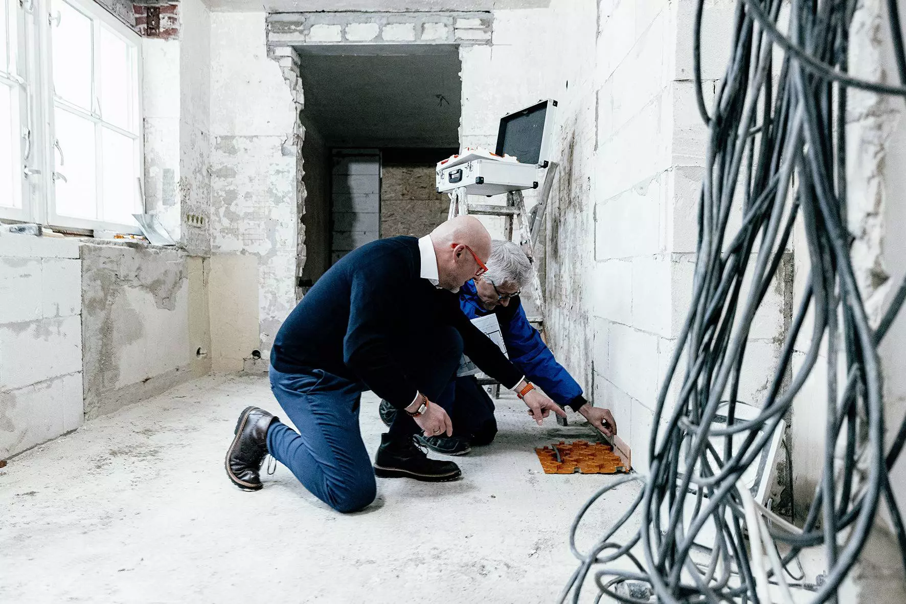 Twee bouwplanners meten de hoogte voor een BEKOTEC-THERM-vloerverwarming op de bouwplaats van een renovatieproject