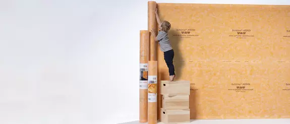 Een jongetje bekijkt verschillende Schl&uuml;ter-KERDI-afdichtingsproducten.