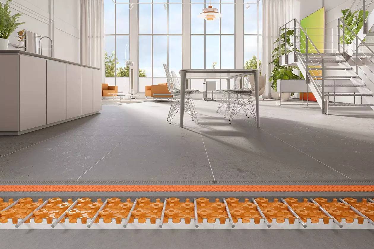 Sistema constructivo de calefacci&oacute;n por suelo radiante BEKOTEC-THERM debajo de baldosas grises de gran formato en una cocina abierta al sal&oacute;n grande y moderna