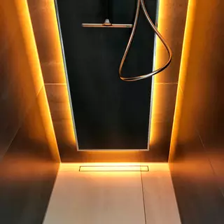 Duschr&uuml;ckwand mit einem Wandpaneel, das mit warmem, orangefarbenem Licht hinterleuchtet ist