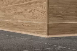 Buitenhoek van de wand met tegels in houtlook en bijpassende plint met hetzelfde patroon