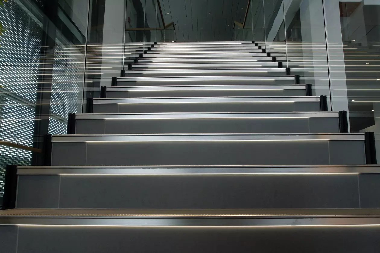 Close-up auf eine breite beleuchtete Treppe mit Fokus auf den grau gefliesten Stufen