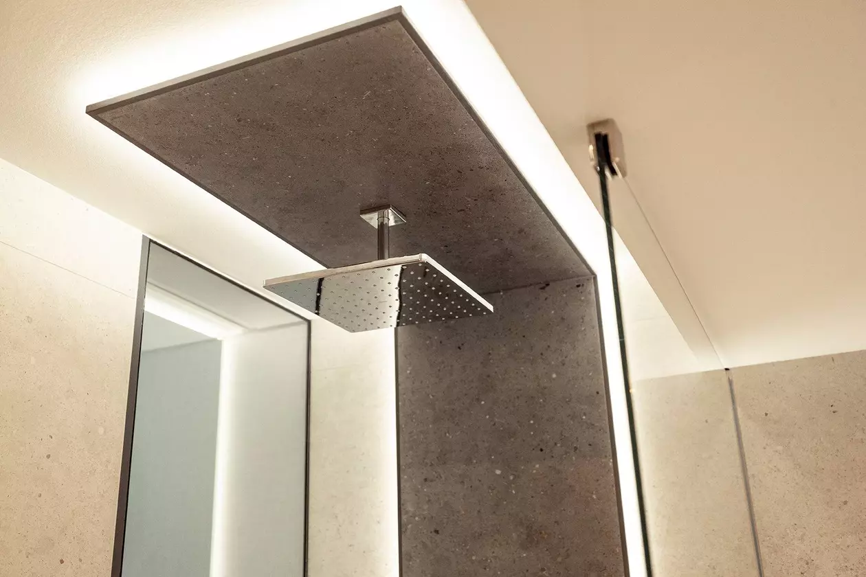 Decke und Wand einer Regendusche mit hellem, indirekt beleuchtetem Wandpaneel