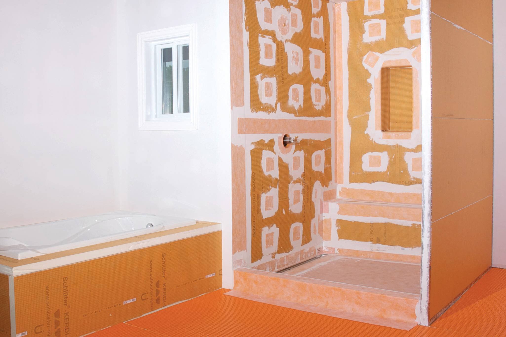 Salle de bain en construction avec les panneaux et membranes oranges de Schluter