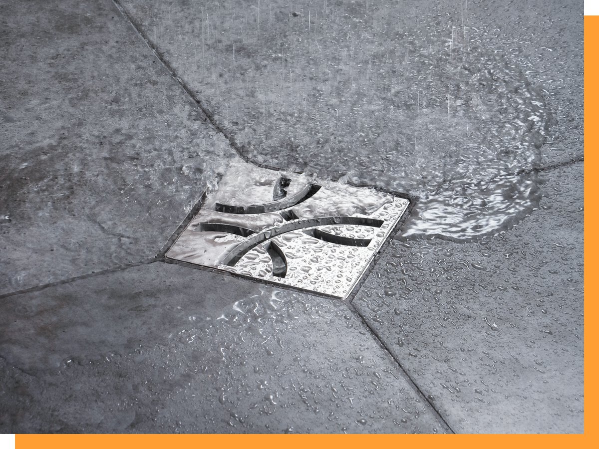 Water flowing across a tiled commercial shower floor toward the drain