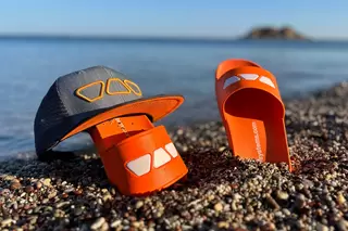 Schl&uuml;ter-Badeschlappen stecken am Strand im Sand