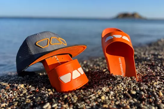 Schl&uuml;ter-Badeschlappen stecken am Strand im Sand