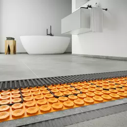 Badkamer met grote grijze tegels, waaronder de elektrische oppervlakteverwarming op de vloer is gelegd.
