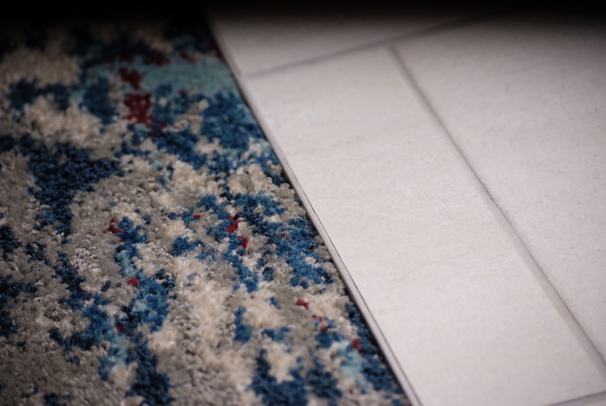 Profilé Schluter-SHIENE qui sépare la moquette du carrelage blanc.