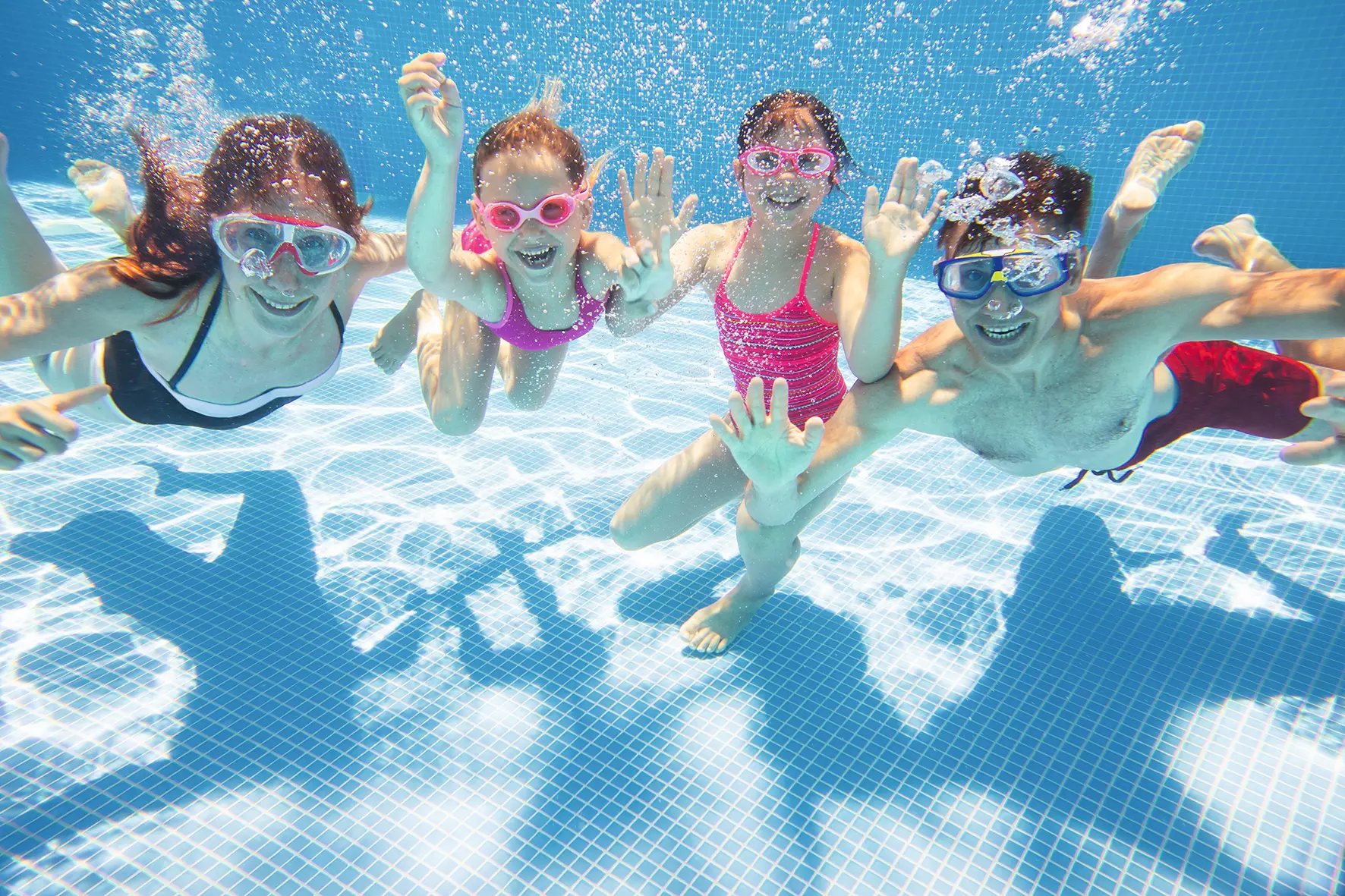Una alegre familia de cuatro miembros se ve bajo el agua en una piscina