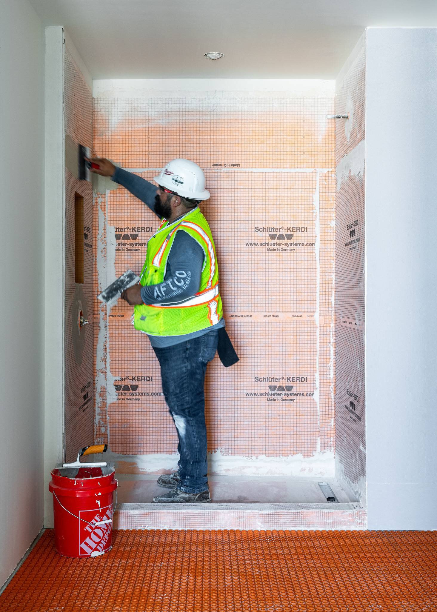 Un installateur travaillant sur une douche avec la membrane d'étanchéité Schluter.