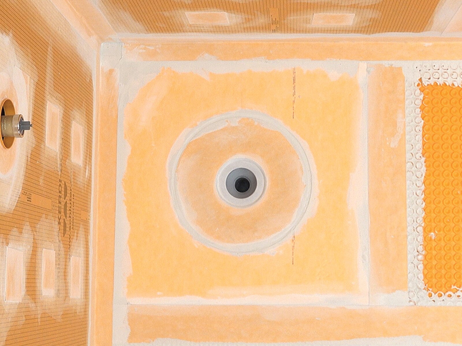 Overhead view of Schluter Systems KERDI shower waterproofing meeting DITRA uncoupling at the curbless transition