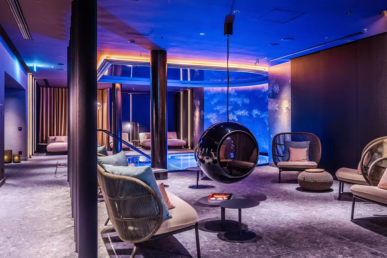 Blau beleuchteter Hotelpool mit Lounge-M&ouml;beln davor