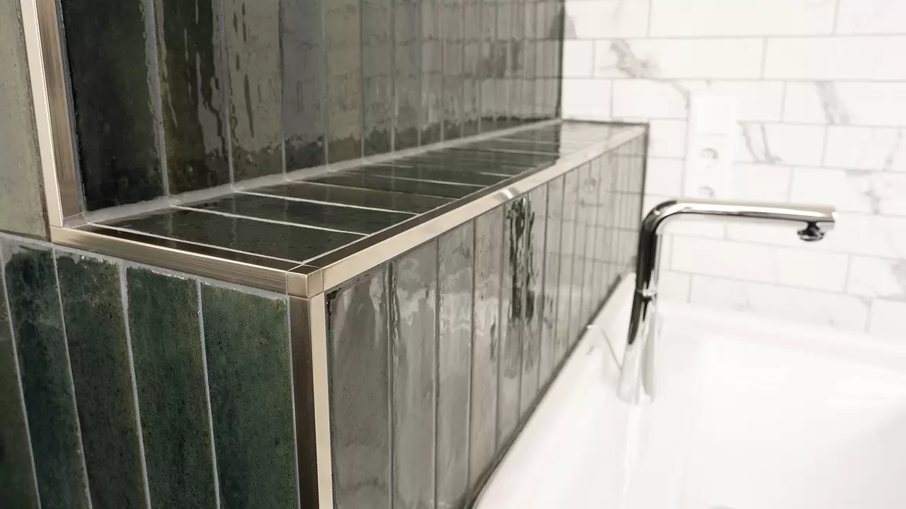 Waschbecken mit dunkelgr&uuml;n gefliester Ablage und QUADEC-Abschlussprofilen in Edelstahl