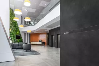 Prostor vstupu do budovy s bordurov&yacute;m profilem s potiskem na stěně, kter&yacute; ukazuje cestu do lobby.