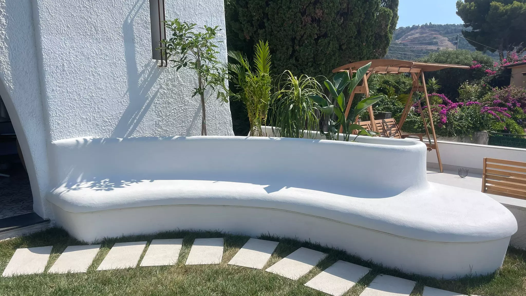panchina bianca sinuosa con piantumazione integrata su una terrazza