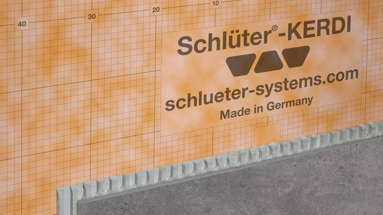 Die orangene Schl&uuml;ter-KERDI-200 Abdichtungsbahn an einer Wand verklebt und teilweise schon mit einer grauen Fliese belegt