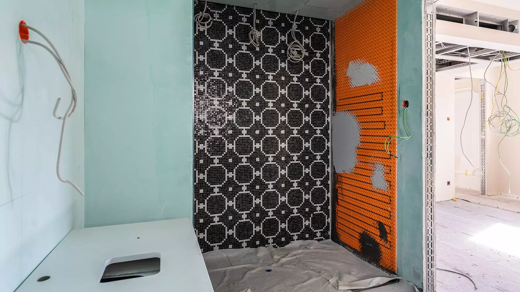 Cuarto de ba&ntilde;o en proceso de renovaci&oacute;n en la parte hist&oacute;rica del edificio del hotel con calefacci&oacute;n DITRA-HEAT-E en la pared derecha de la ducha
