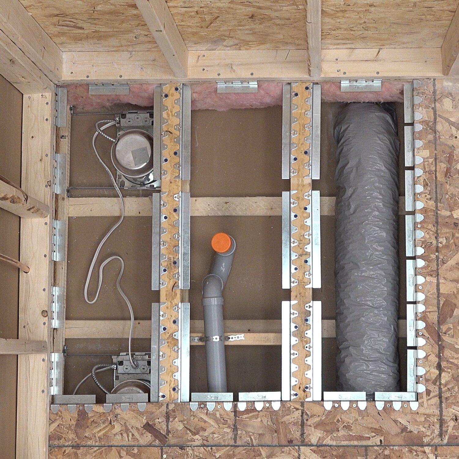 Curbless shower floor recessed with Schluter Systems KERDI-SHOWER-FRS brackets around wiring, drain and ductwork