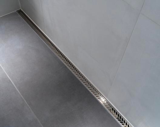 Douche avec un drain Kerdi-Line Vario Herringbone de Schluter sur fond de tuile grise