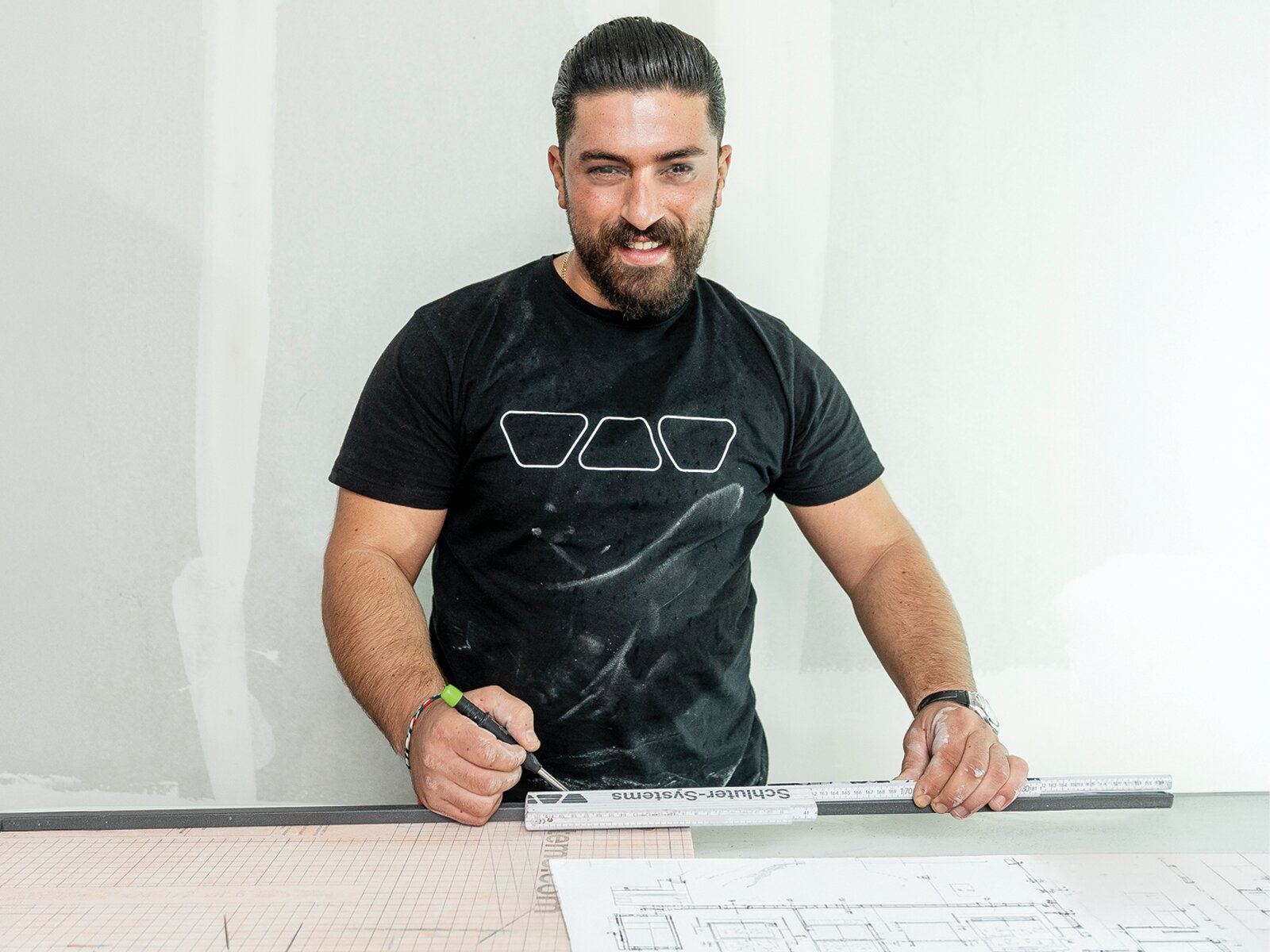 Installer planning a curbless shower installation with layout drawings and a Schluter Systems straightedge