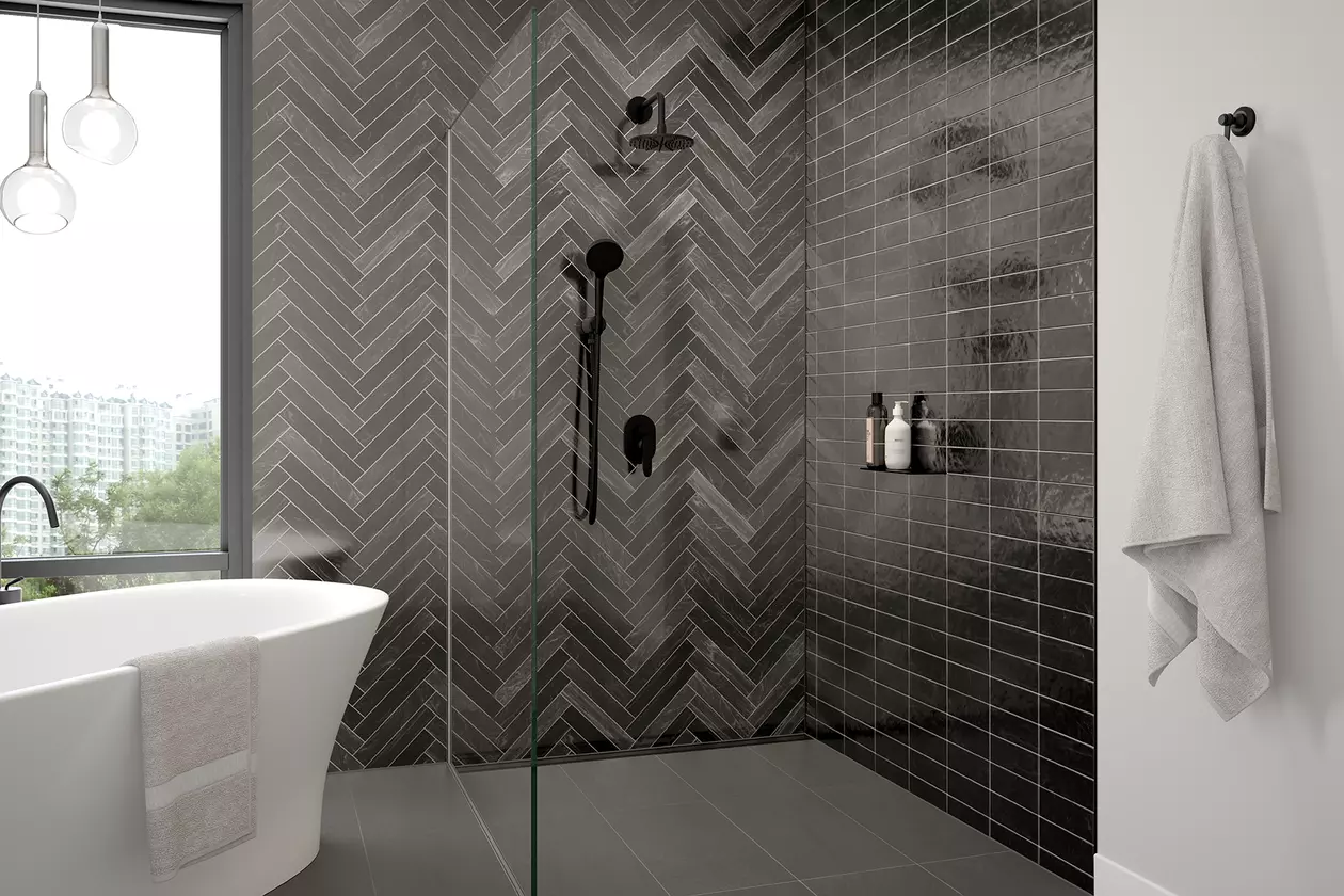 Caniveau Schl&uuml;ter-KERDI-LINE et tablette SHELF en finition MGS, noir graphite mat, mis en œuvre dans une salle de bains moderne avec douche &agrave; l'italienne, carrelage de couleur gris fonc&eacute;, baignoire sur pied et robinetterie noire.