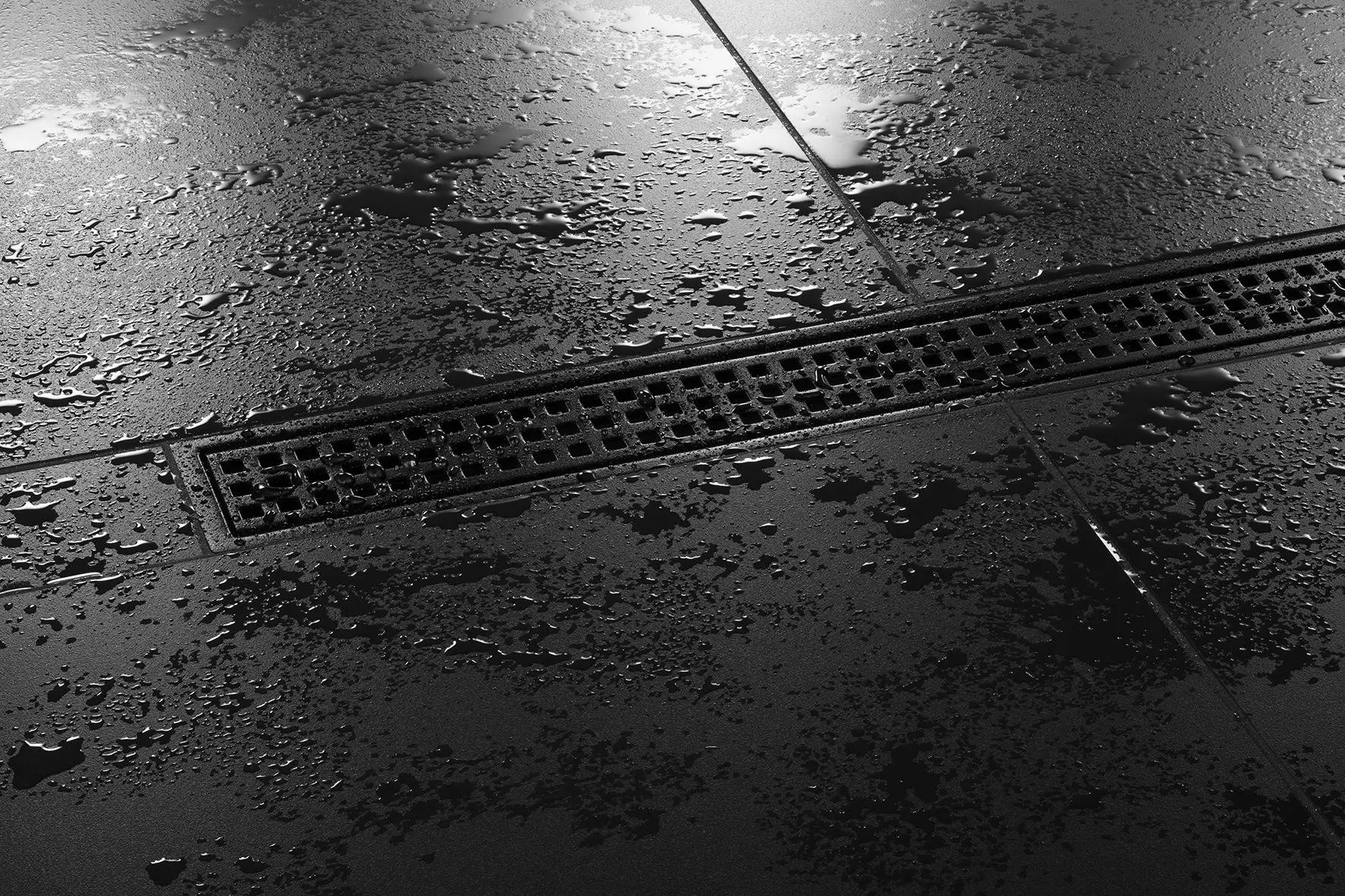 Gros plan sur le caniveau Schl&uuml;ter-KERDI-LINE-B design SQUARE en finition noir graphite mat dans une douche &agrave; l'italienne avec carrelage noir.