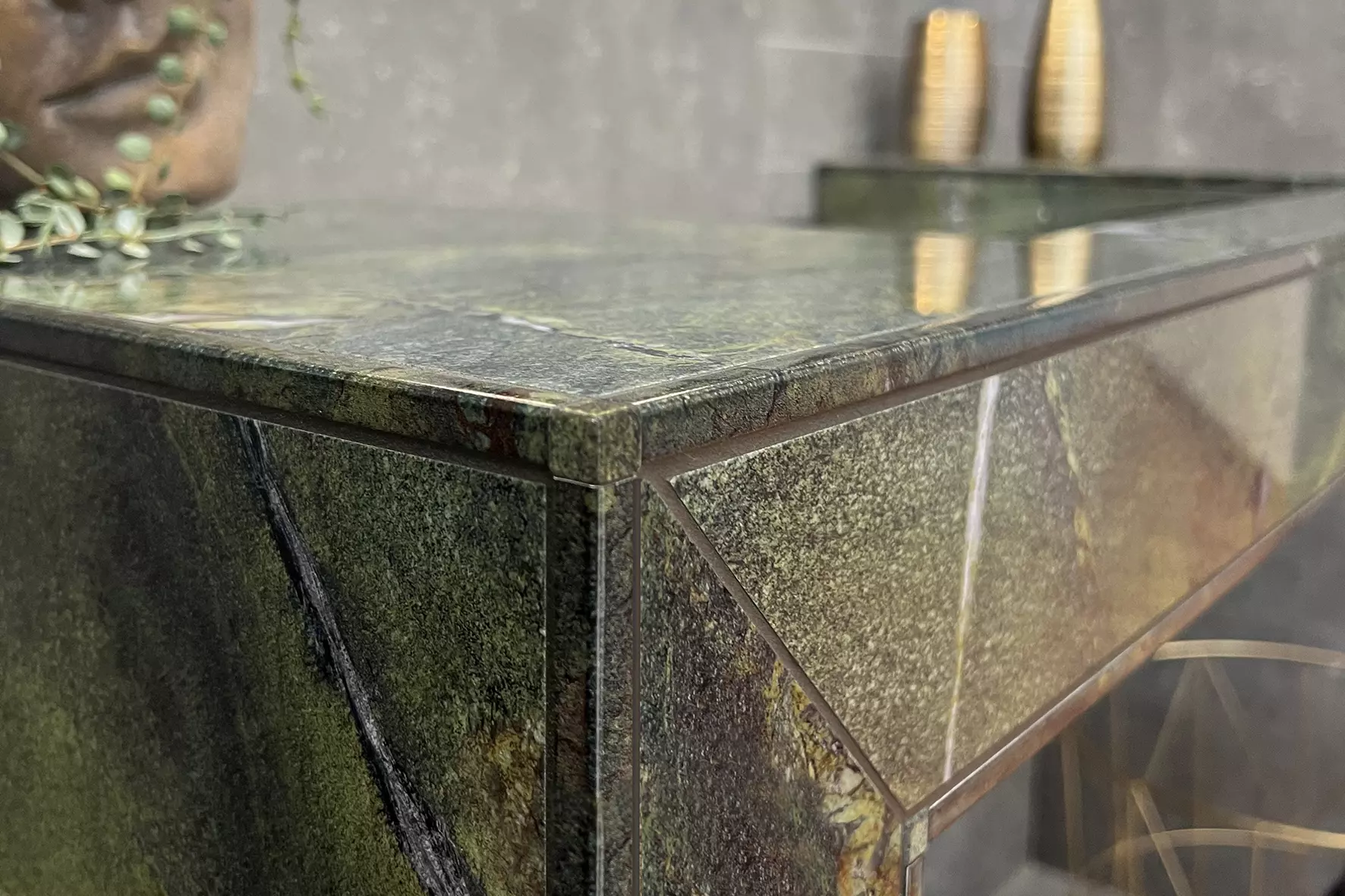 Hoek van een betegelde halfhoge planchet met groene marmertegels en bedrukte randprofielen in tegeldesign