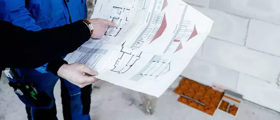 K&eacute;t &eacute;p&iacute;t&eacute;sz megn&eacute;zi egy ingatlan alaprajz&aacute;t, hogy megtervezze a BEKOTEC-THERM padl&oacute;fűt&eacute;s be&eacute;p&iacute;t&eacute;s&eacute;t