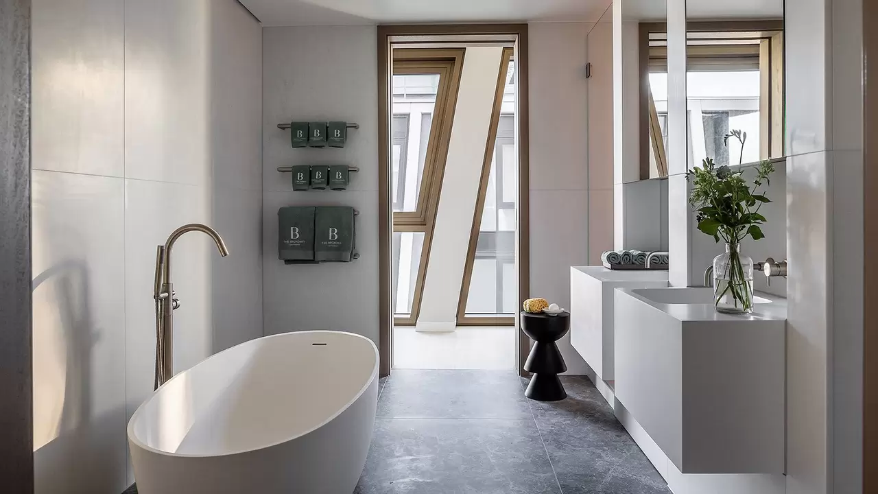 Bathroom in ‘The Broadway’ with free-standing bathtub and two wall-mounted vanity units.