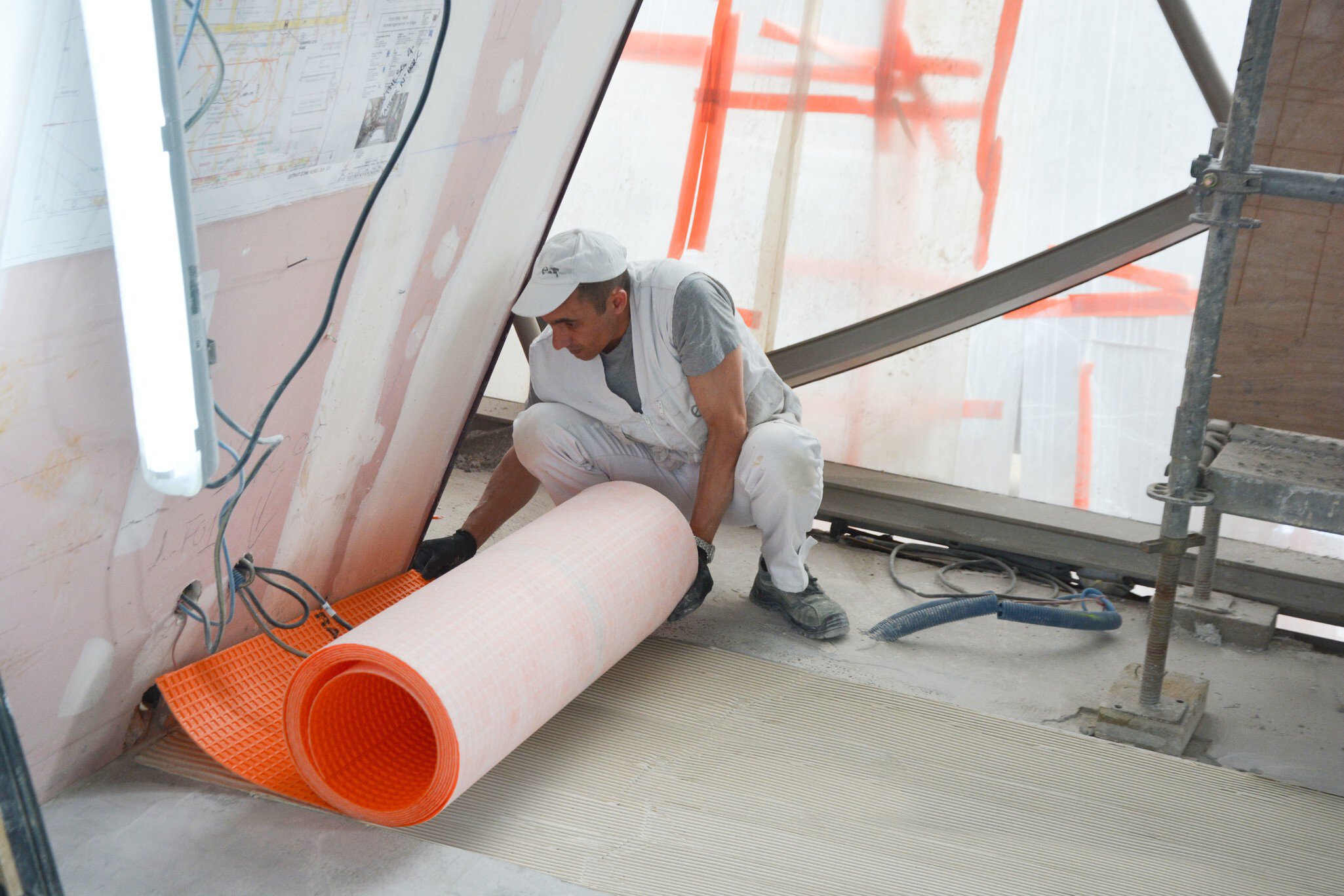 Un installateur déroule un rouleau de membrane DITRA de Schluter Systems sur la Tour Eiffel.