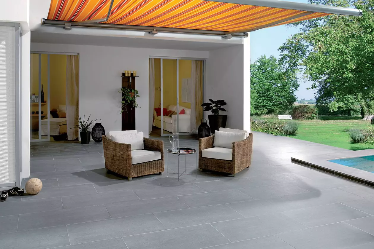 Deux chaises sont plac&eacute;es sur la terrasse d'une maison avec un jardin attenant.