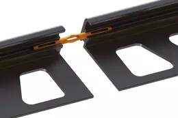 Vista detallada del conector Schl&uuml;ter-JOLLY-V parcialmente insertado entre dos perfiles de protecci&oacute;n de cantos JOLLY en negro texturizado MGS