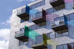 Perfiles de distintos colores en los balcones de la fachada exterior de un edificio.