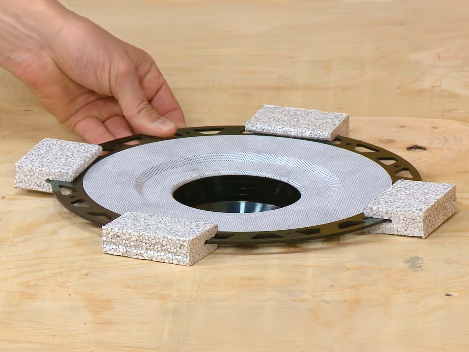 Schluter Systems KERDI-DRAIN bonding flange held during a curbless shower installation rough-in