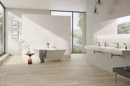 Ljust badrum med klinker i tr&auml;design, frist&aring;ende badkar och dubbelt tv&auml;ttst&auml;ll