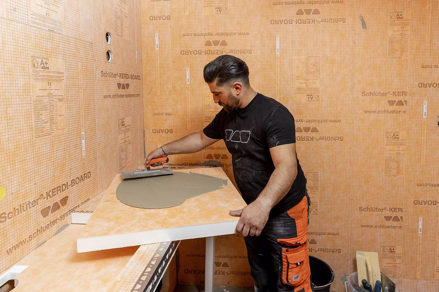 Trabajador instalando la impermeabilizaci&oacute;n de paredes utilizando el panel constructivo Schl&uuml;ter-KERDI-BOARD.