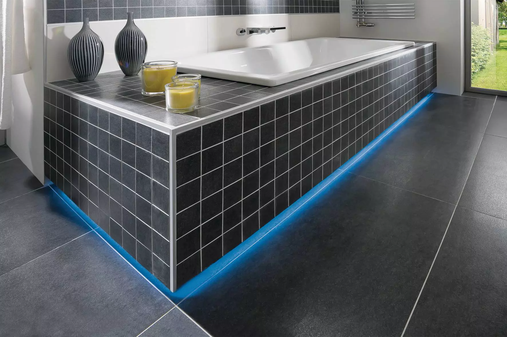 Salle de bain moderne avec carrelage de couleur sombre et baignoire &eacute;clair&eacute;e