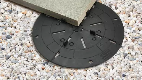 Schl&uuml;ter-TROBA-LEVEL-LV 3 in een kiezelbed onder een terrastegel